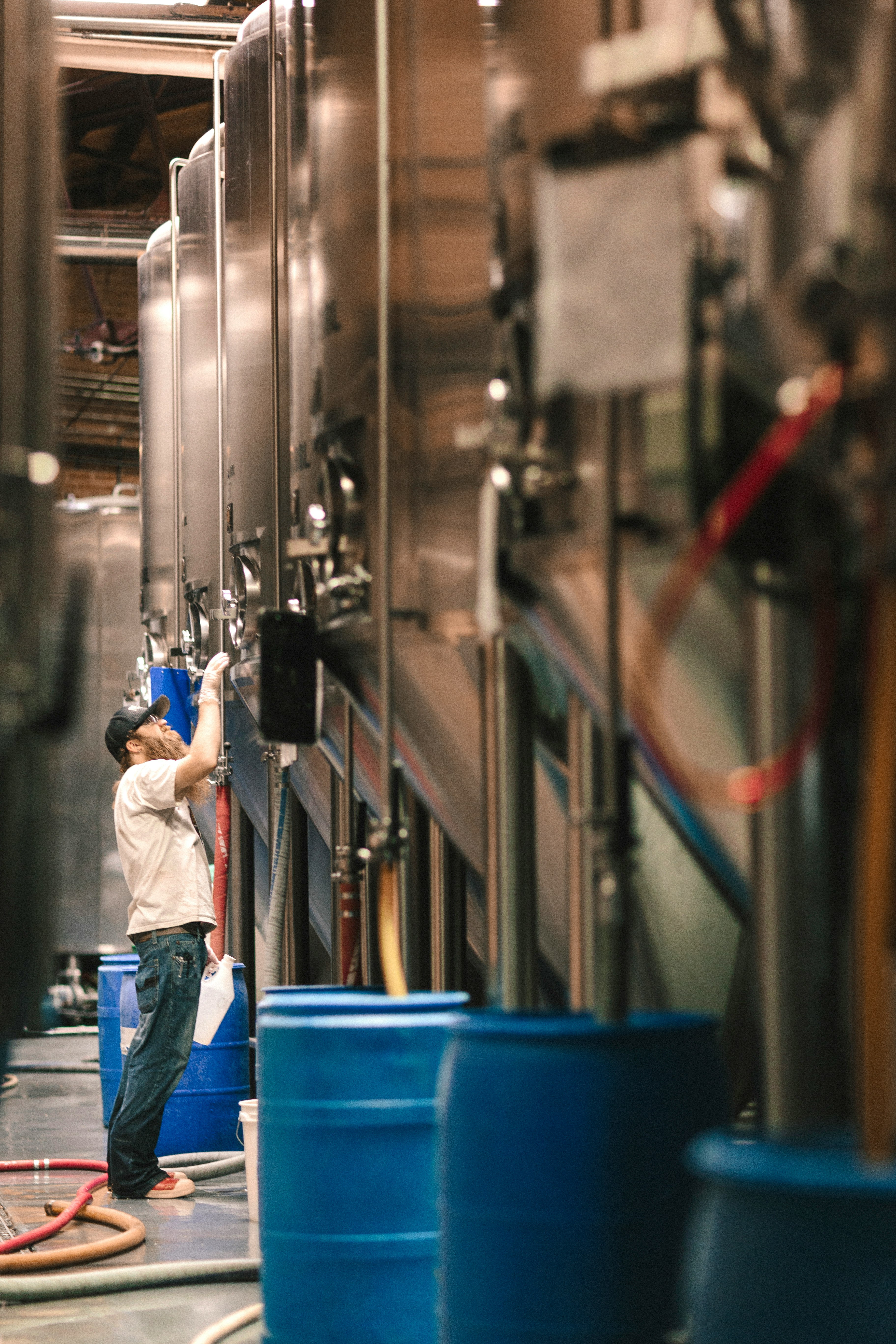 man in white crew-neck top and blue jeans standing in front of storage tank